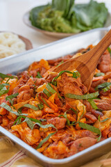 고추장 양념의 닭갈비를 나무 주걱으로 섞고 있는 모습