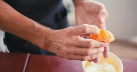 A professional chef combines a rice ball with a piece of salmon and presses them together, making salmon nigiri, traditional Japanese cuisine