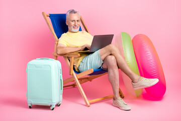 Full body photo of professional traveling pensioner businessman sit sunbed wait his plane booking hotel isolated on pink color background