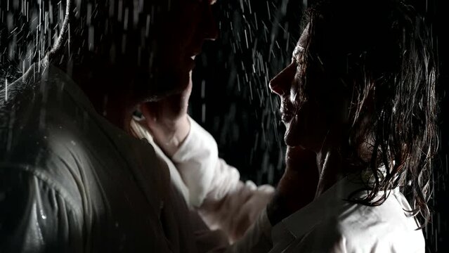 tender and passion embrace of two lovers in rain in night, closeup view of man and woman in darkness
