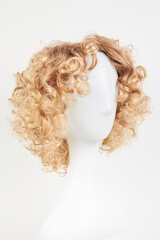 Natural looking blonde fair wig on white mannequin head. Short hair cut on the plastic wig holder isolated on white background.