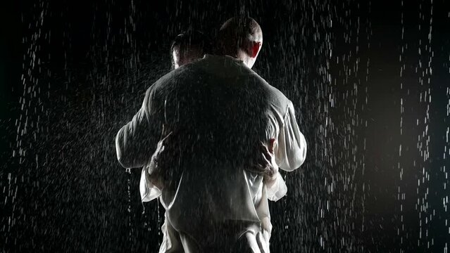tender embrace in heavy rain, silhouette of man and woman hugging in night, male brawny back