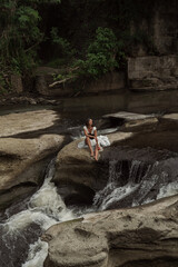 A beautiful girl washing clothes in the open air. River and tropical wood.