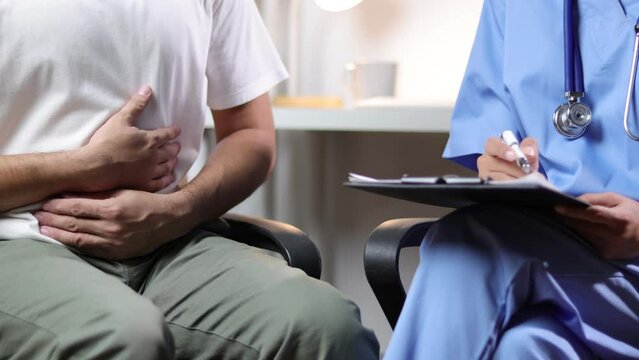 The doctor is diagnosing a male patient with abdominal pain in a hospital examination room.