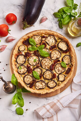 Quiche open tart pie with eggplant, sundried tomatoes and chicken meat. Savory taste. Top view.