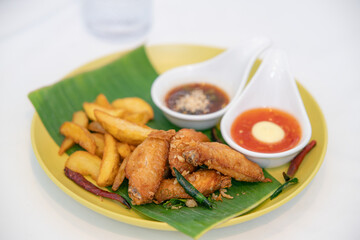 fried chicken with french fried on a banana leaf