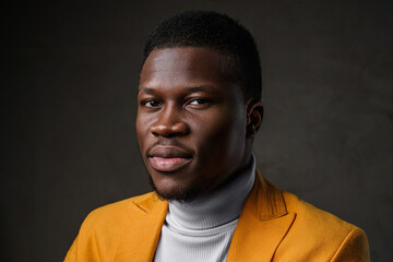 Obraz premium Portrait of a smartly dressed black man in a yellow blazer with short hair against a dark backdrop
