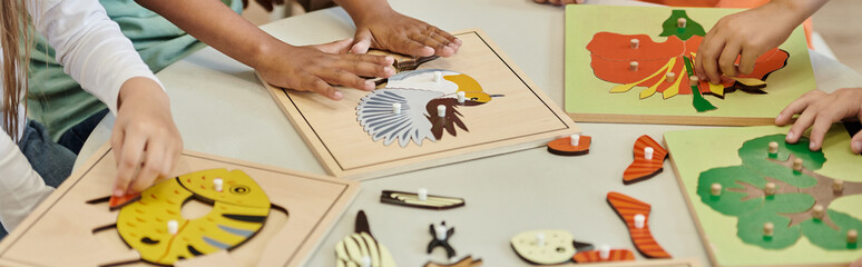 partial view of kids playing with didactic materials during lesson in montessori school, banner