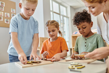interracial kids playing with didactic montessori material near teacher in school, learn and play - obrazy, fototapety, plakaty