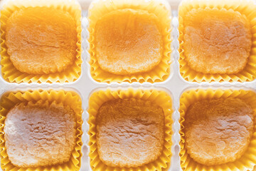 Elegant homemade coconut candies in yellow punnet. Cupcake papers filled with creamy cakes. Delicious sweets cooked at home. Sweet food receipt. Traditional Japanese sweets mochi served on golden tray