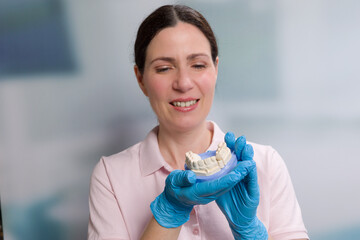 female dentist / dental technician is presenting a dental imprint with artificial dentition ready for use