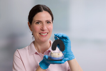 female dentist / dental technician is presenting a dental imprint with artificial dentition ready for use