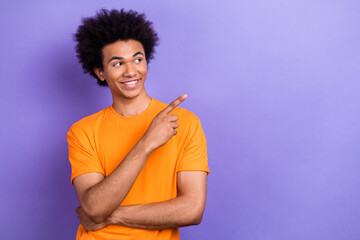 Photo of attractive cheerful man toothy smile look indicate finger empty space isolated on violet...