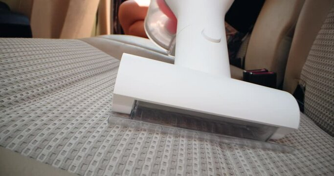 A woman's hand vacuums the seat in the middle of the car. Cleaning the car from garbage and dirt. High quality 4k footage