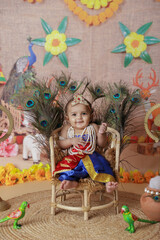 Janmashtami Concept. Cute baby boy dressed up as little krishna sitting on chair.