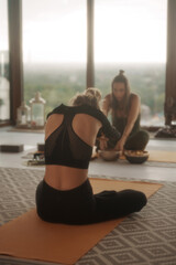 Fototapeta premium Girls in sportswear engaging in yoga and meditation during a group session in an apartment overlooking the cityscape