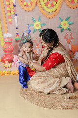 Janmashtami Concept. Mother sitting with her cute baby boy dressed up as little krishna.