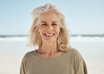 Portrait, beach and senior woman with a smile, retirement and travel with tourist, summer vacation and wellness. Face, old person and traveler on seaside holiday, Canada and weekend break for peace