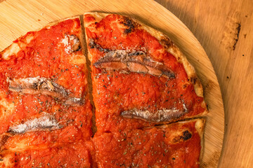 Pizza tonda cotta nel ruoto in un forno elettrico condita con sugo di pomodoro, olio, acciughe e...