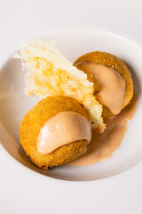 Polpette ripiene di pulled pork e servite con salsa rosa e cialda di parmigiano come antipasto in un pub