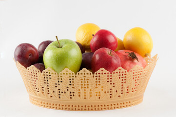 Fresh colourful fruits in a modern design plastic basket, isolated on white