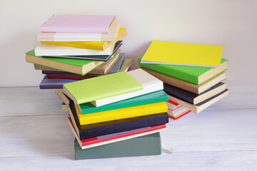 Stacks of different colorful books on rustic table. Copy space