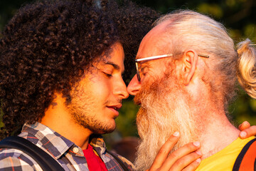 Celebrate the beauty of love's diversity with this heartwarming image. A gay couple of different ages and races share a joyful moment, embracing and smiling brightly amidst the serene beauty of nature