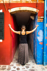 Una donna infelice si appoggia ad un arco rosso e blu a Burano, isola della laguna di Venezia