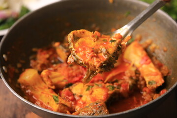 indian fish curry served with rice in a bowl closeup with selective focus and blur
