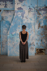 Una donna di spalle davanti a un muro azzurro rovinato di una casa di Burano, isola della laguna di...