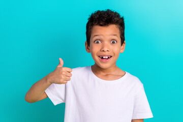 Photo of surprised amazed boy wear trendy white clothes thumb up wow cool special offer shop sale isolated on cyan color background