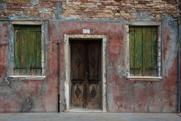 Fototapeta na wymiar Il muro rovinato della facciata di una casa disabitata a Burano, isola della laguna di Venezia
