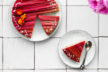 Rhubarb cake with geometric pattern with pink peonies on a white stone background. Spring and summer sweet-sour healthy dessert. Close-up view