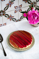 Rhubarb cake with geometric pattern with pink peonies on a white stone background. Spring and summer sweet-sour healthy dessert. Close-up view