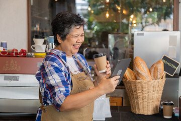 Happy aging society people lifestyle with modern technology tablet concept, Healthy Asian senior elderly retired woman coffee small business owner barista employee receive order by using application