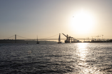 Bridge, boats and industrial cranes - sunset over the river