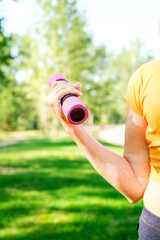 Senior woman going sport exercises with dumbbells on summer park. Active lifestyle concept.