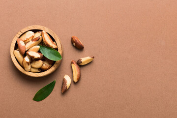 Fototapeta na wymiar Fresh healthy Brazil nuts in bowl on colored table background. Top view Healthy eating bertholletia concept. Super foods
