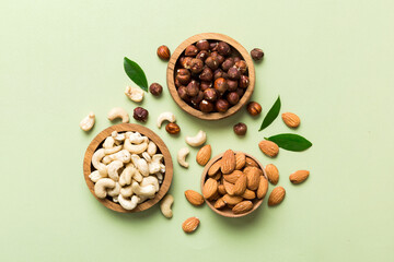 Assortment of nuts in wooden bowl on colored table. Cashew, hazelnuts, walnuts, almonds. Mix of nuts Top view with copy space