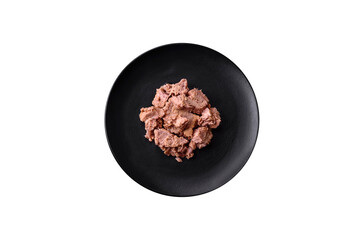 Delicious canned tuna meat on a black ceramic plate on a dark concrete background