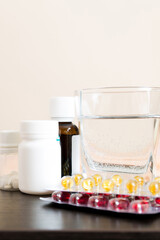 Attractive sick pregnant woman is lying in sofa. Taking pills from colds