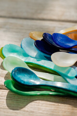 pile of colorful acrylic teaspoons in sunlight outside on wooden patio table