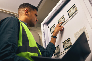 Man, maintenance and control room with laptop, electrician with inspection and fixing electricity supply. Check power grid, pc software and engineering, fuse box and technician with quality assurance