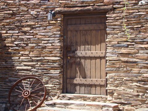 old wooden door with stone house and wagon wheel