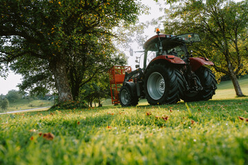 Obraz premium red machine tractor on bright green grass 