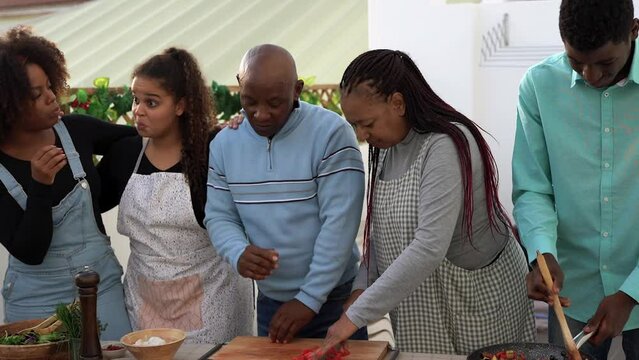 Happy african family having fun cooking together healthy food at house terrace druing summer time 

