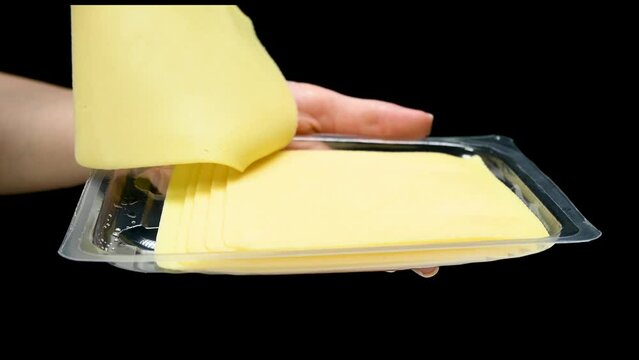 Transparent packaging with cheese slices in hand taking holding on black background isolation