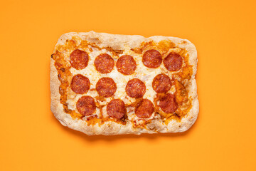Pepperoni pizza on bright orange background with copy space, top view