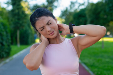 Young fitness woman holding her sports injury neck, muscle painful during training