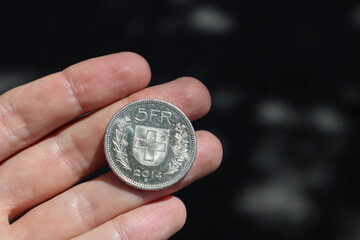 Close-up of a 5 Swiss franc coin held by a man's hand